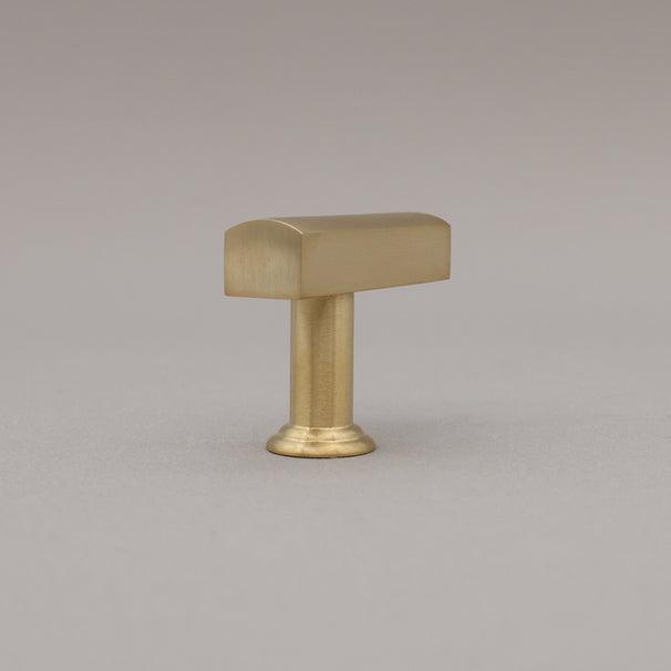 Unlacquered satin brass t-knob standing on a gray background rear view