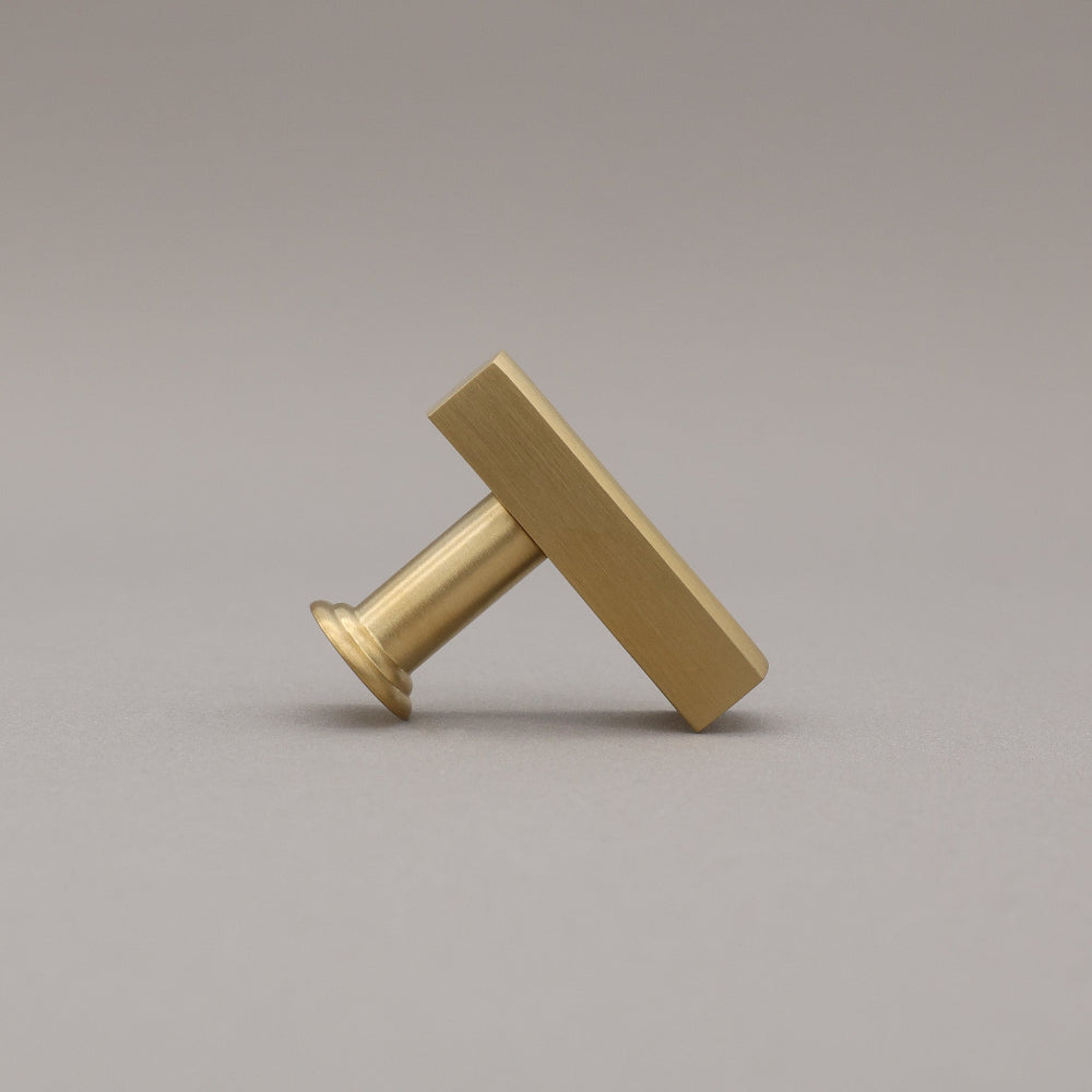 Unlacquered satin brass t-knob standing on a gray background side view