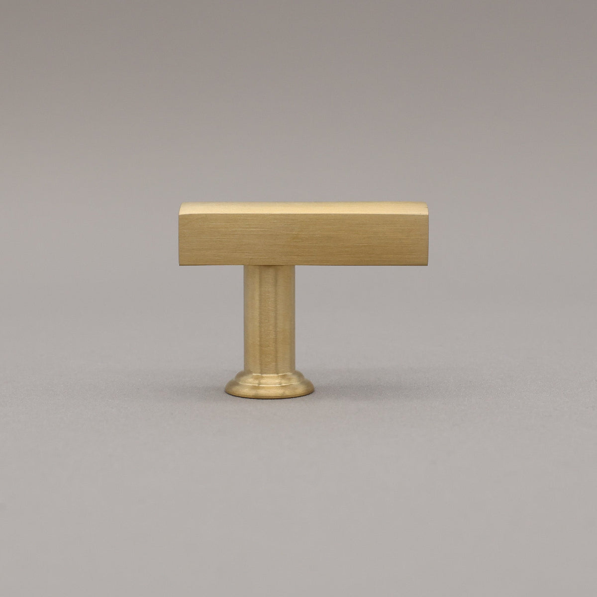 Unlacquered Satin brass t-knob in the mod solid brass collection on a gray background