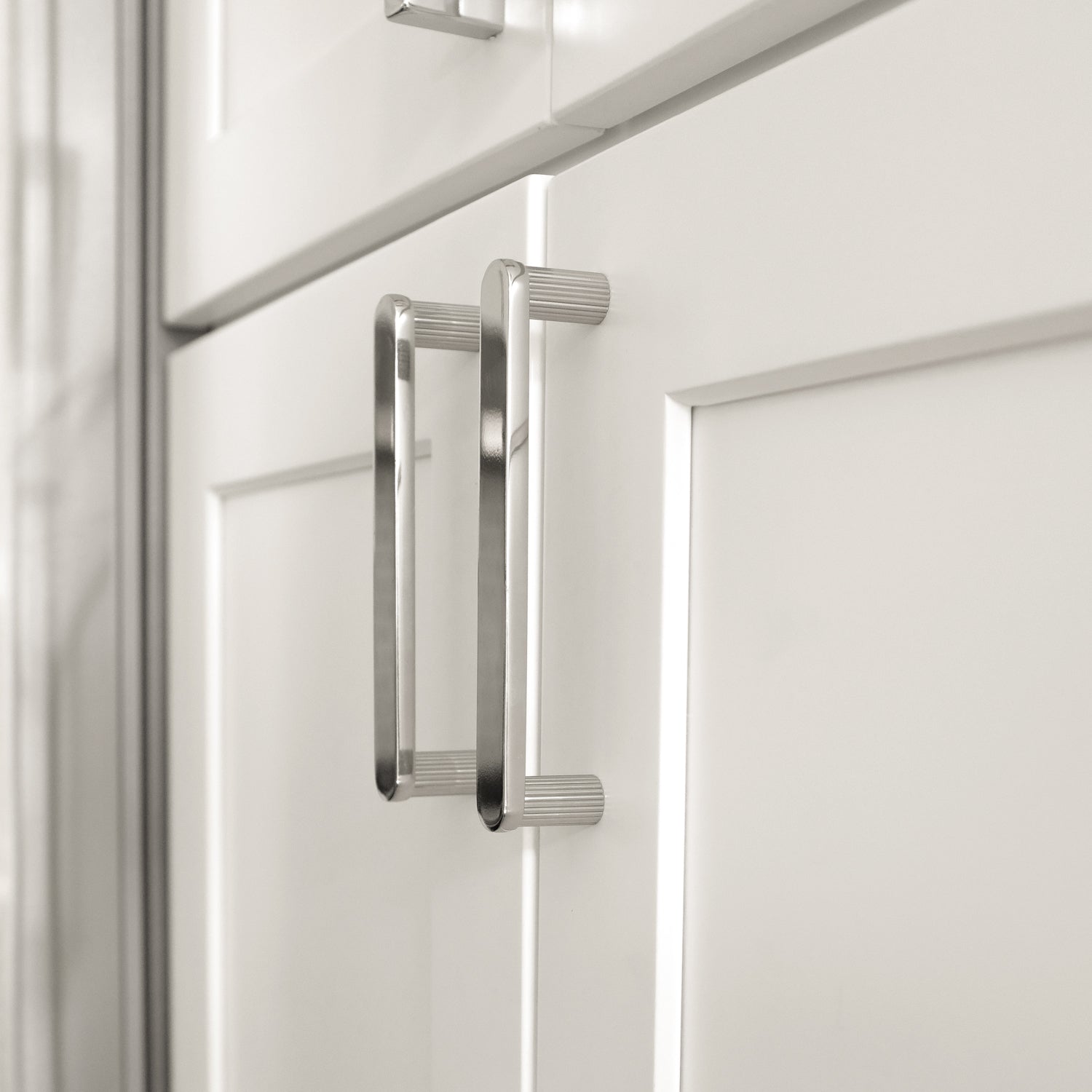 Modern Kitchen Cabinet Handles in a Polished Finish on White Cabinet Doors.