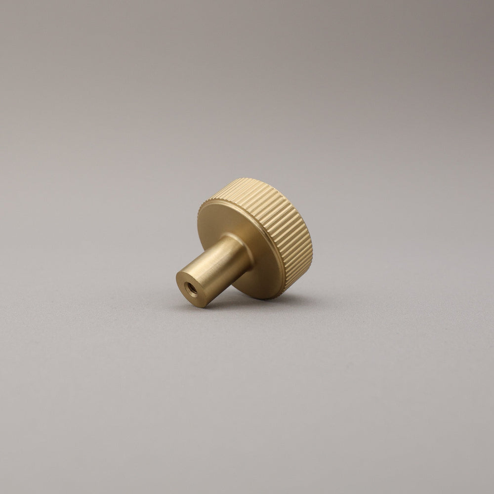 Satin brass finished brass knob on a gray background.