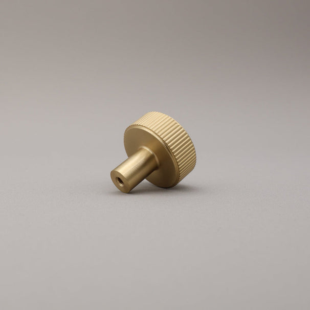 Satin brass finished brass knob on a gray background.