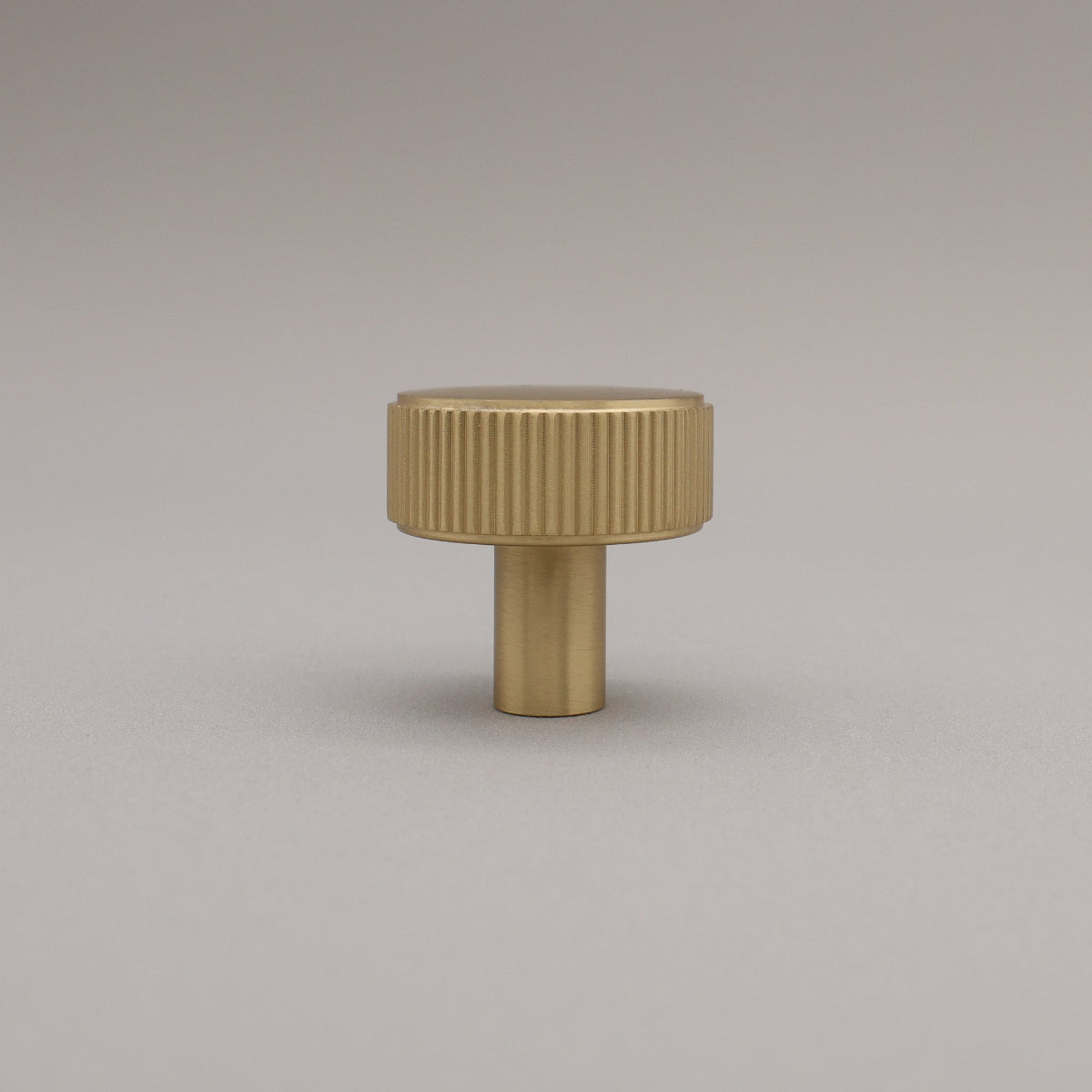 Standing brass knob on a gray background.
