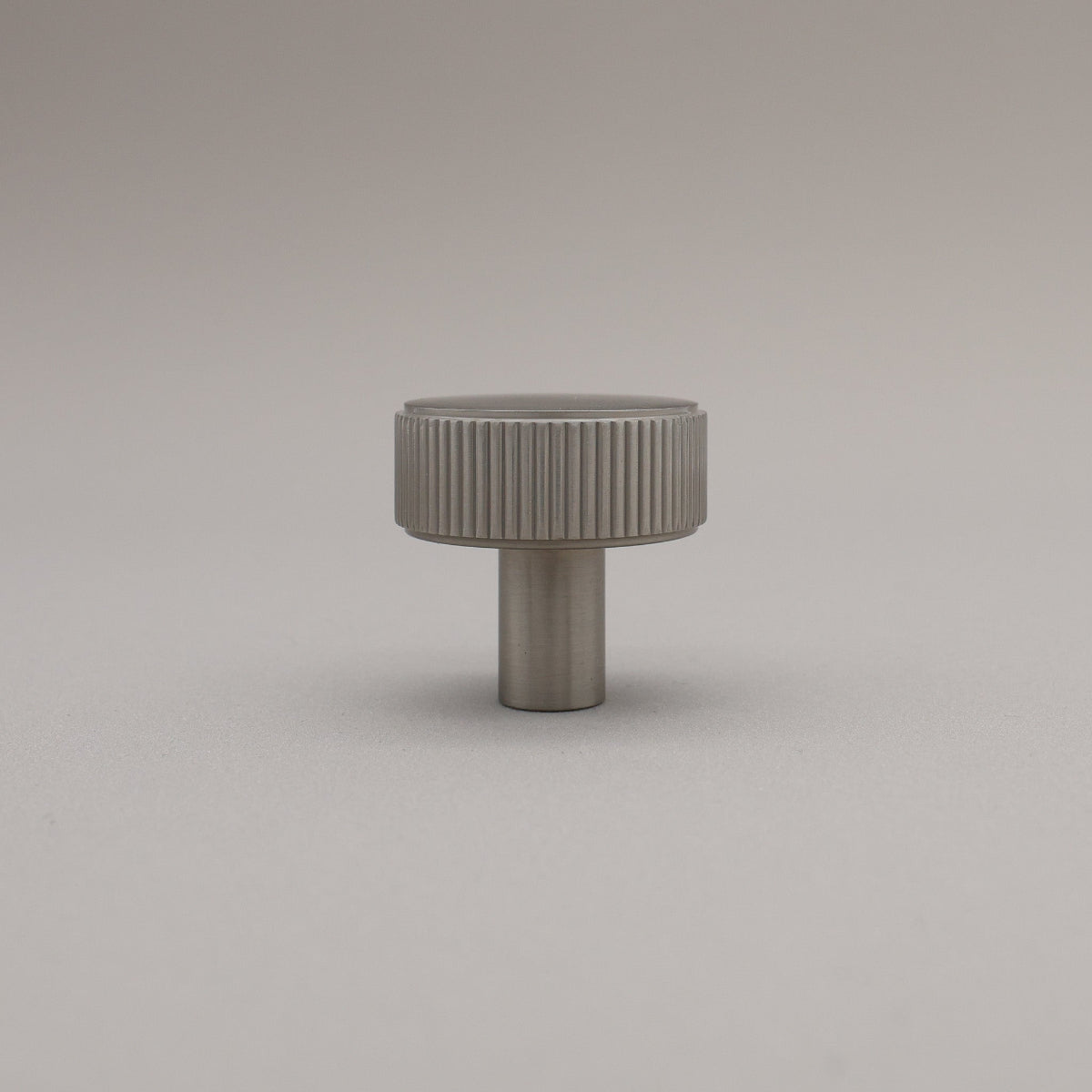 Gray textured cylindrical knob on a light gray background