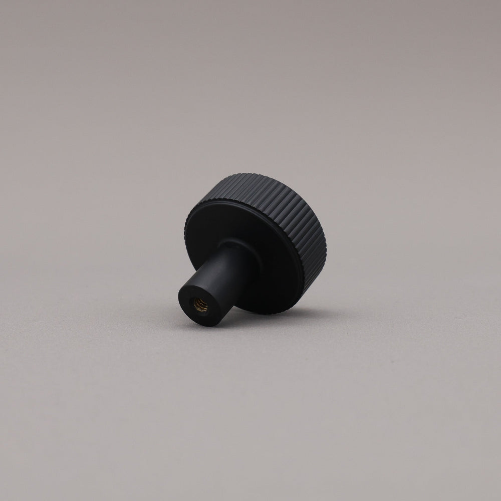 Black textured knob on a gray background