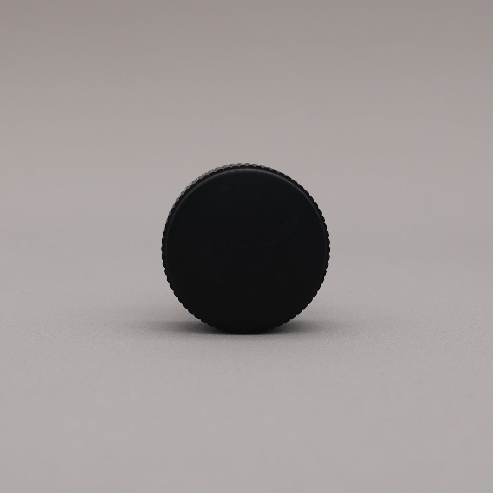 Black circular knob on a gray background
