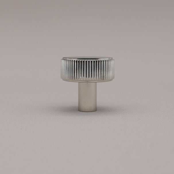 Polished nickel fluted ribbed knob on gray background standing upright.