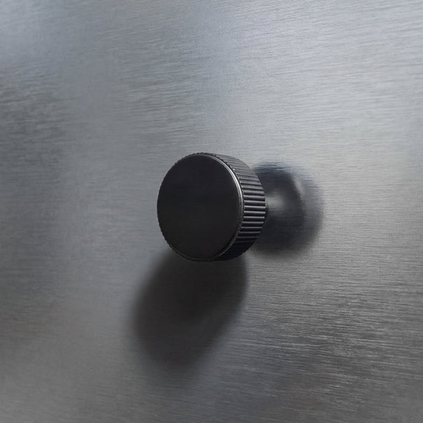 Black fluted textured knob on a stainless steel drawer.