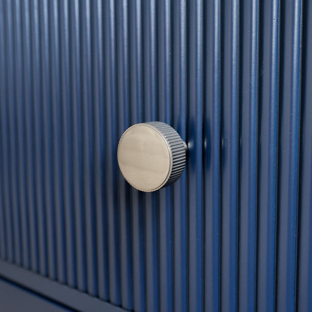 satin nickel silver textured ribbed knob with fluting detail installed on a fluted blue cabinet drawer