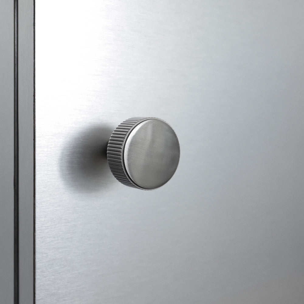satin nickel silver textured ribbed knob with fluting detail installed on a stainless steel cabinet