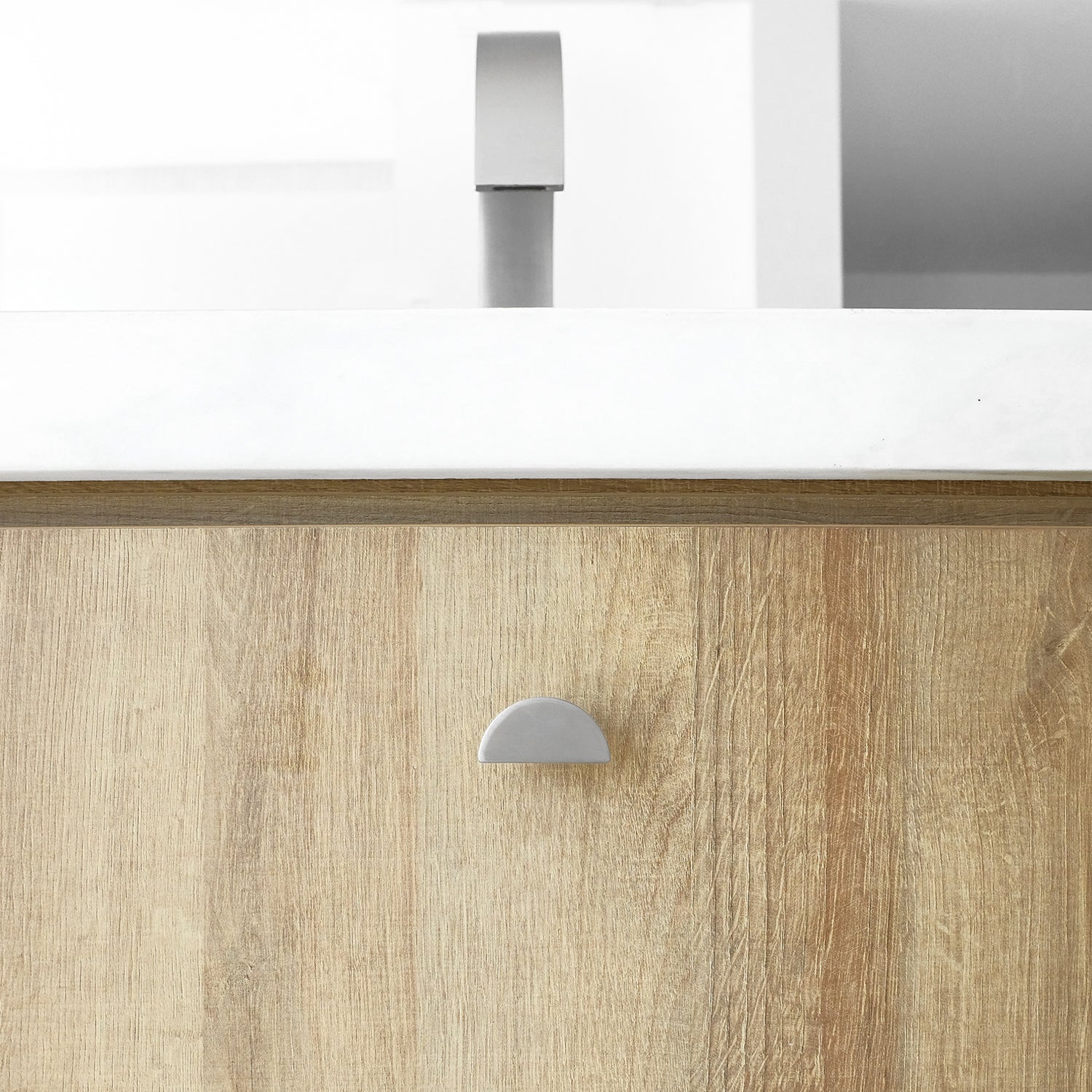 Satin nickel half moon knob on bathroom wooden drawer.