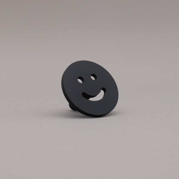 Matte Black smiley face object on a gray background