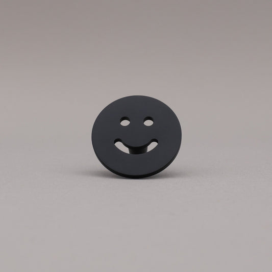 Satin brass smiley face knob button on a gray background.