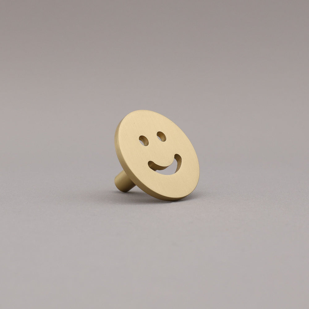 Satin brass smiley face object on a gray background