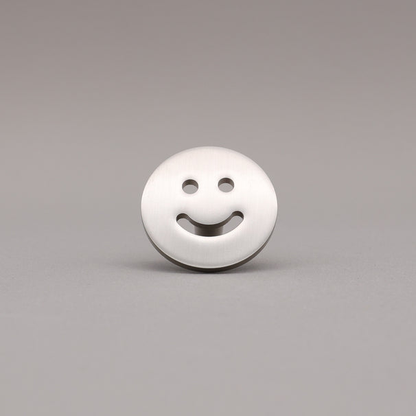 Smiley face knob finished in Satin Nickel on a gray background.