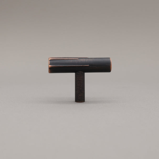 Sunburst t-knob made out of venetian bronze on a grey background.
