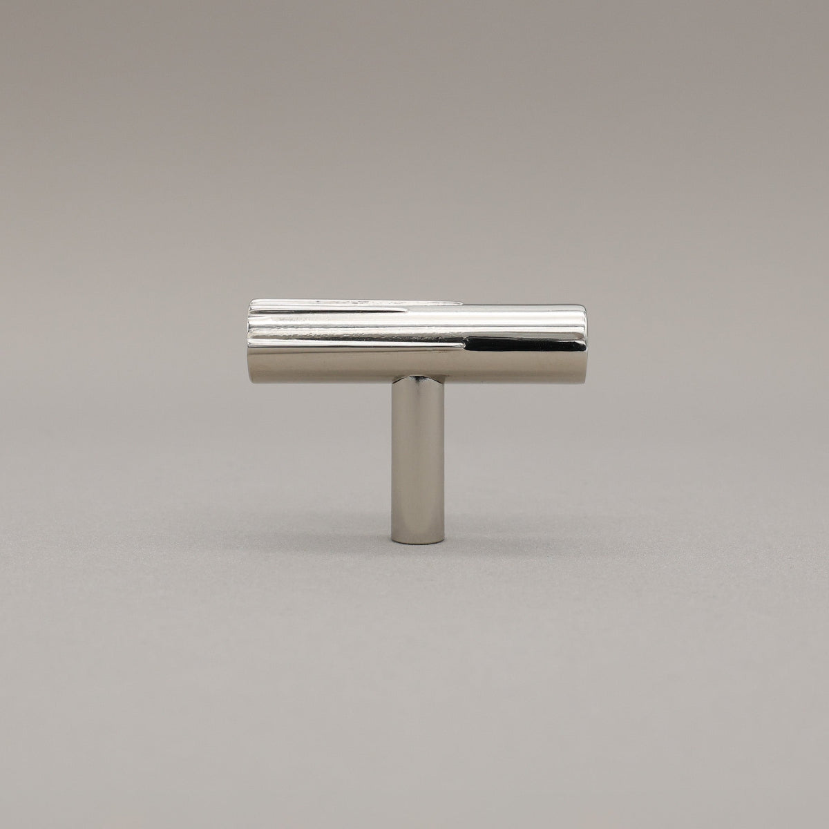 Pollished Nickel art deco knob on a gray background.