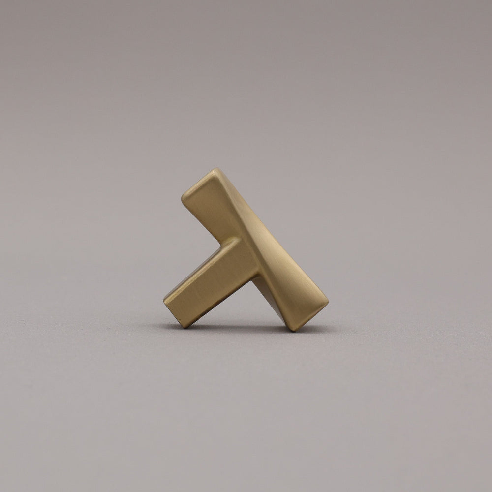 Satin Brass twisted knob on a gray background leaning.