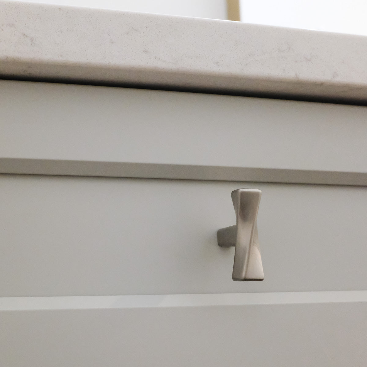 Twist Knob in Satin Nickel on Gray Cabinet Drawers.