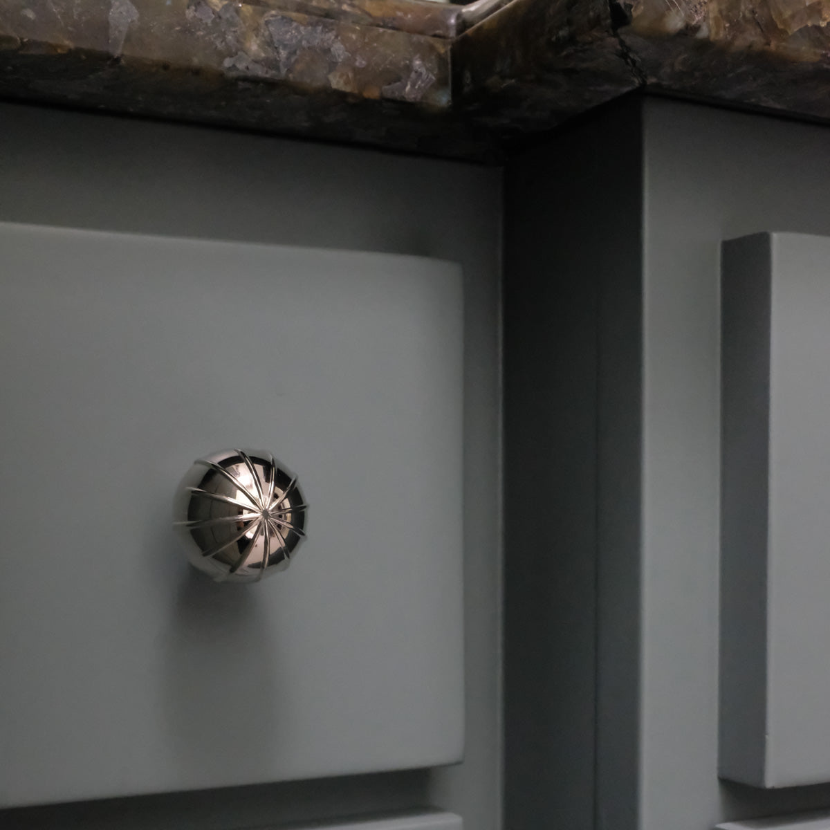 Polished Nickel contemporary knob with architectural lines that is round on blue bathroom vanity drawer