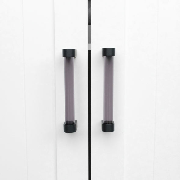 Two Clarity 96mm center to center cabinet pulls in Smoke Acrylic and Matte Black installed on white cabinet doors