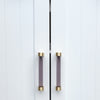 Two Clarity 96mm center to center cabinet pulls in Smoke Acrylic and Satin Brass installed on white cabinet doors