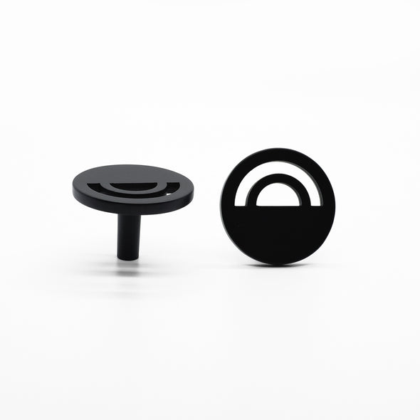 Two Matte Black Hapny Horizon knobs, one standing and one front-facing while laying down