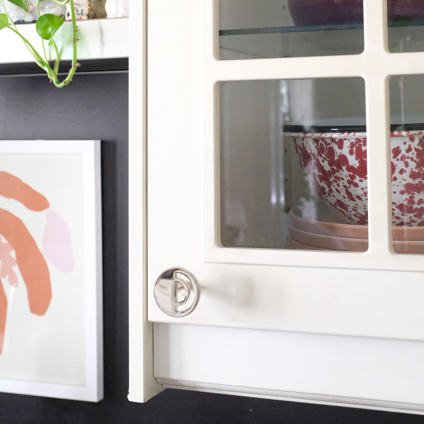 Polished Nickel Hapny Horizon knob installed on white cabinet door with glass panels