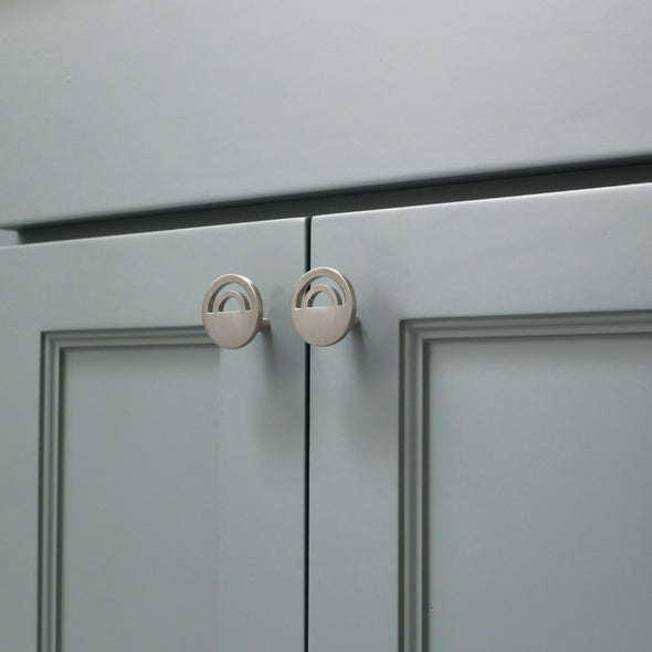 Angled view of two Satin Nickel Hapny Horizon knobs installed on blue cabinet doors