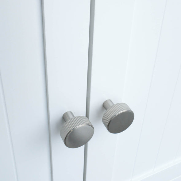 Two Satin Nickel Hapny Ribbed knobs installed on white cabinet doors