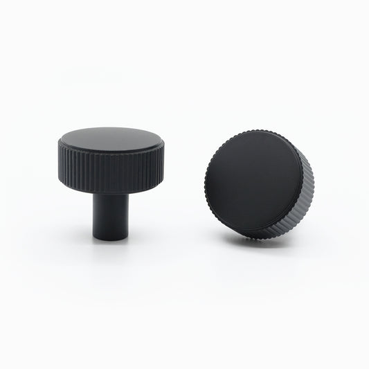 Black textured knob on a stainless steel drawer.