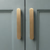 Head-on view of two Hapny Ribbed 5" cabinet pulls in Satin Brass finish installed on blue cabinet doors