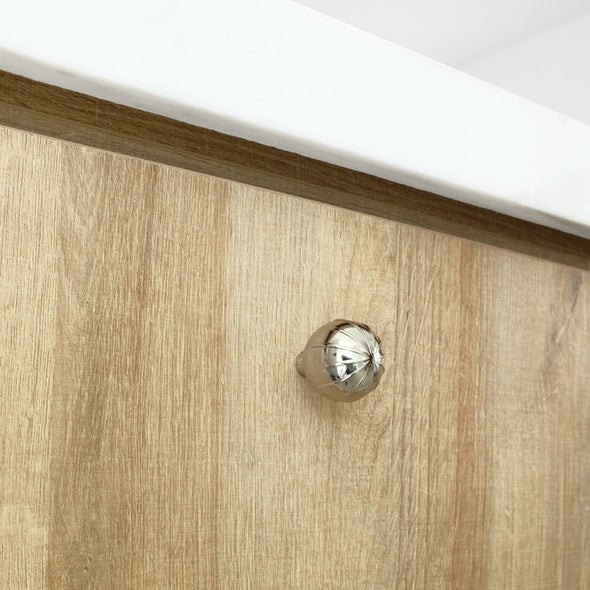 One Polished Nickel Hapny Sunburst knob installed on a wooden cabinet door with a white marble countertop