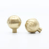 Two Satin Brass Hapny Sunburst knobs, one standing and one side-facing while laying down