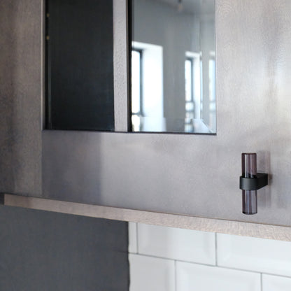 Acrylic cabinet knob in black finish on dark kitchen cabinets.